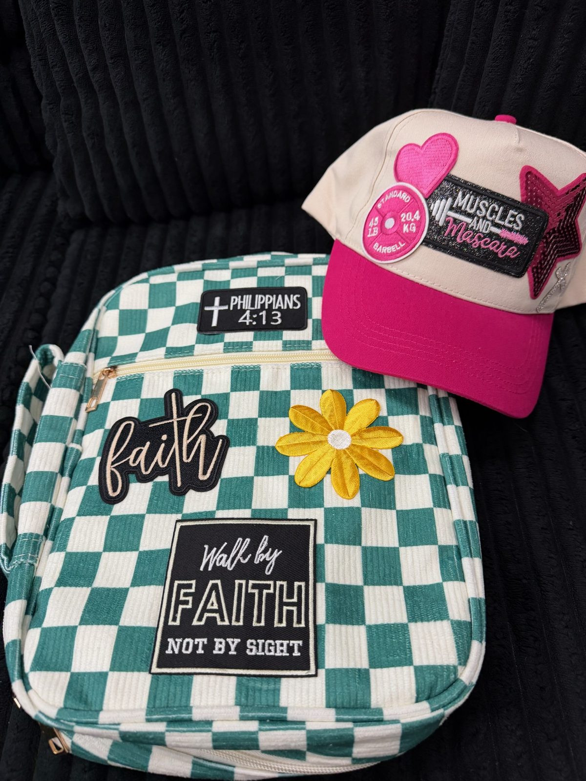 A teal checkered Bible cover set with faith patches, and a pink trucker cap wearing a Muscles and Mascara patch