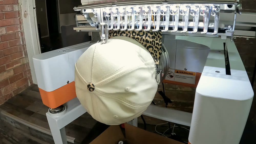 A cap in the hoop on the embroidery machine, part way through a design.