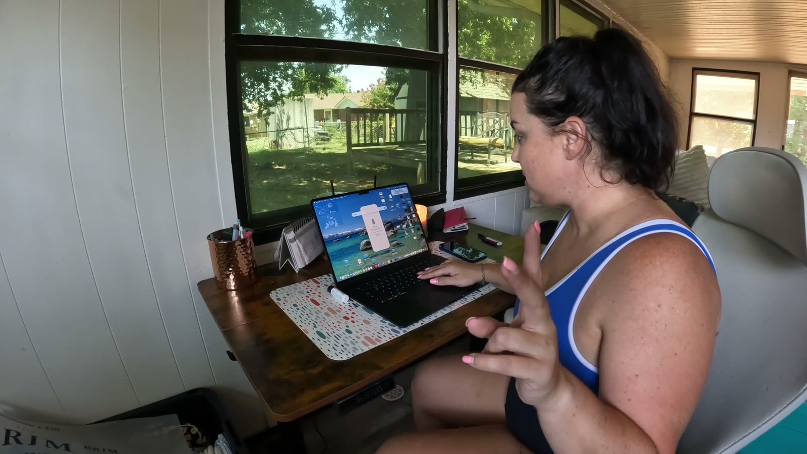 Stephanie at her desk by the window, working on a design on the laptop