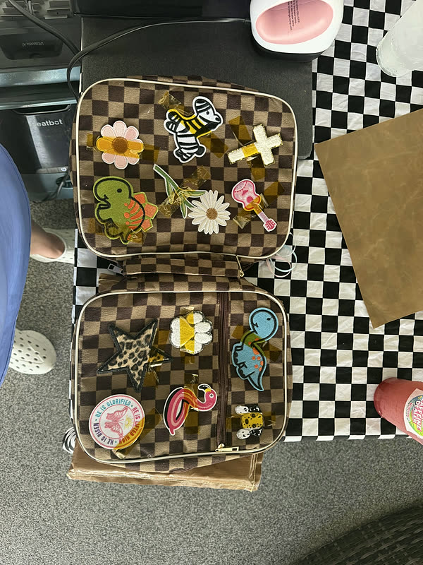 An open case laid on a checkered cloth with loose patches arranged inside it.