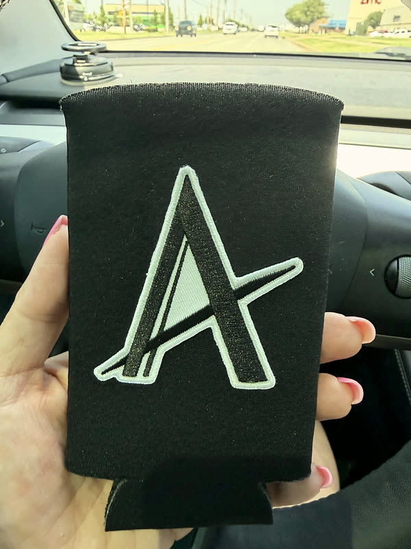 A black slim koozie with one large outlined letter.