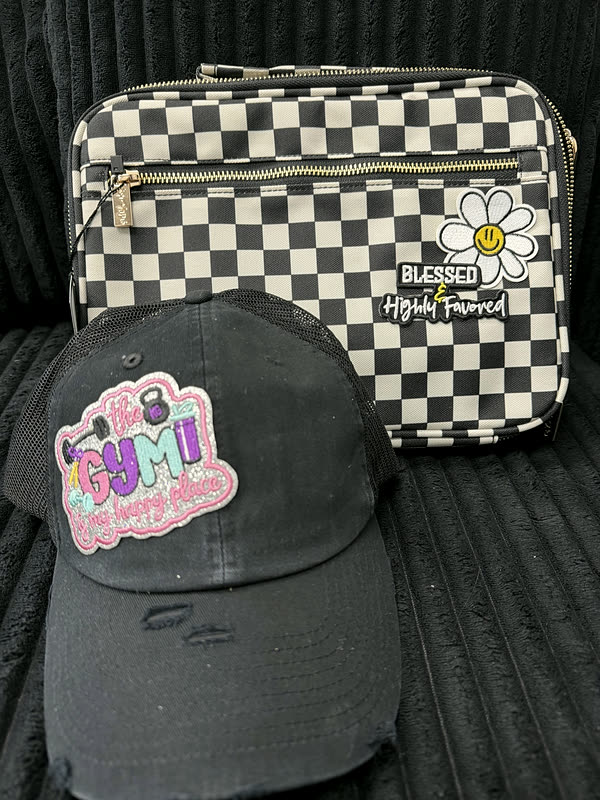A distressed charcoal cap and a black and white checkerboard belt bag, each carrying the same style of patch, on a couch.