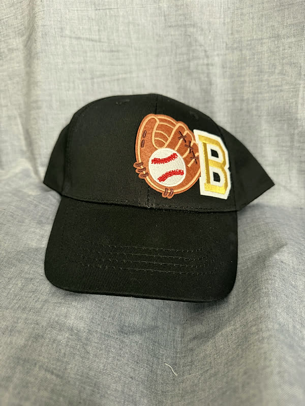 A black cap with a baseball-glove patch and a gold chenille letter set beside it.