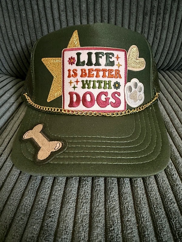 An olive cap with a rectangular dog-themed patch, a star, a paw and a small bone, a gold chain across the brim.