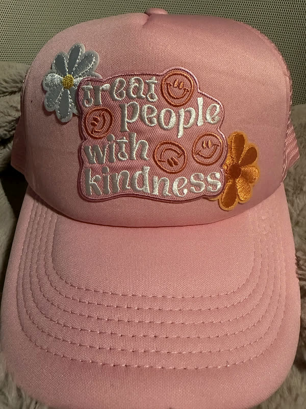 A pink cap with a chenille phrase, small smiley faces and two flowers worked across the crown.