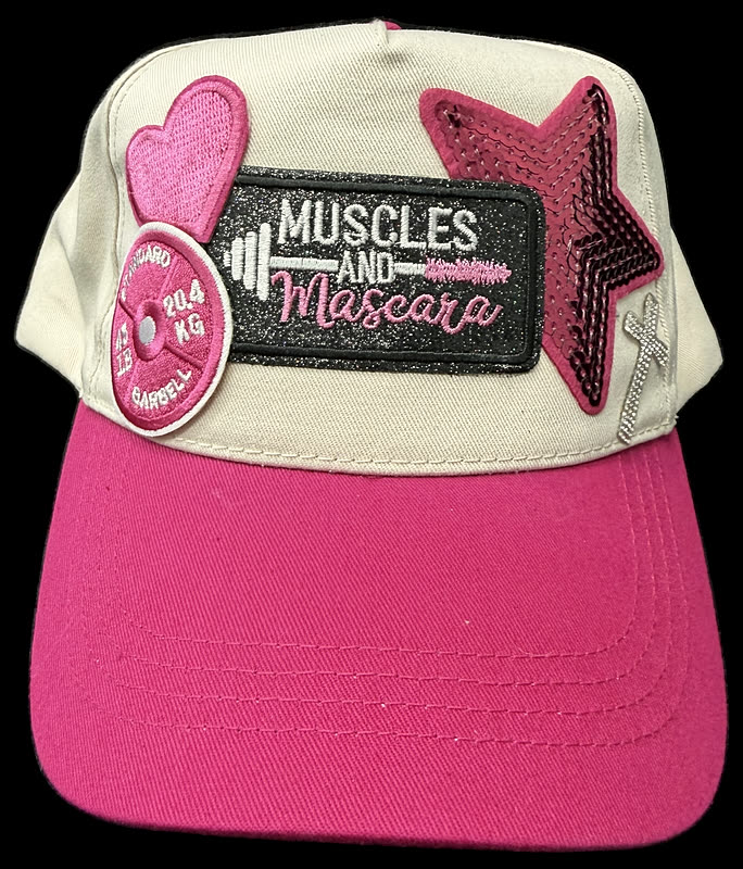 A cream and pink trucker cap with a rectangular word patch, a heart and a star, photographed against black.