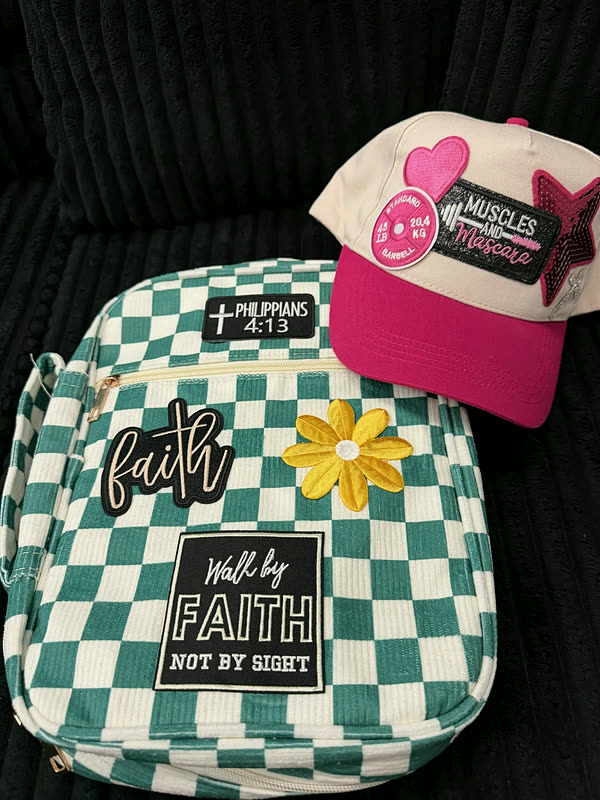 A green checkerboard book cover, a smaller case and a pink cap laid out together, each carrying patches.